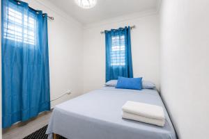 a white bedroom with blue curtains and a bed at Harmonia - Sunbeha resort, Juan Dolio in Juan Dolio