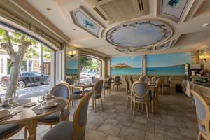 ein Restaurant mit Tischen, Stühlen und Fenstern in der Unterkunft Hôtel Le Rocher in Calvi