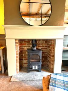 a brick fireplace with a mirror above it at Rustic Retreat cottage in Thirsk