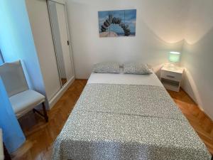 a small bedroom with a bed and a chair at MAG Apartmani in Jezera +6 photos