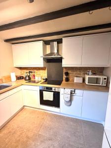 a kitchen with white cabinets and a stove top oven at Rustic Retreat cottage in Thirsk