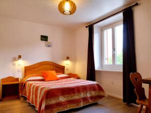 a bedroom with a bed with orange pillows and a window at Hôtel Bellier in La Chapelle-en-Vercors