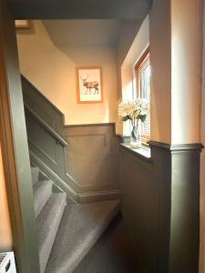 a hallway with stairs and a picture of a cow on the wall at Rustic Retreat cottage in Thirsk