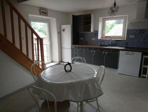 a kitchen with a white table and chairs and a kitchen with a table at Le Logis du Commis in Notre-Dame-dʼElle