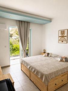 a bedroom with a bed and a large window at Delfini Pearl Stegna Beach in Archangelos