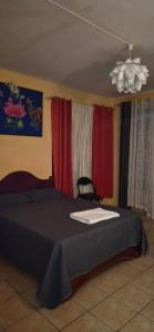 a bedroom with a bed with red curtains and a chandelier at Studio Aiko2 côtière in Mauritius