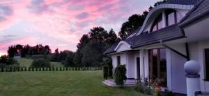 a house with a field and a pink sky at Willa Sielanka in Becejły