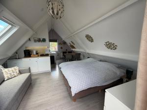 a attic bedroom with a bed and a couch at Logeren op Dijk43 in Broek op Langedijk