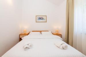a bedroom with a white bed with towels on it at APARTMENTS JELENA 1,2,3,4 & 5 SUPETAR - free parking in Supetar