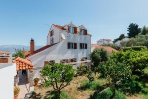 a white house on a hill with trees at APARTMENTS JELENA 1,2,3,4 & 5 SUPETAR - free parking in Supetar