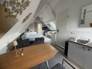 a kitchen and living room with a table and a bed at Logeren op Dijk43 in Broek op Langedijk