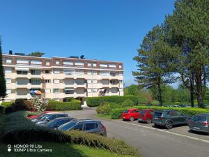 a parking lot with cars parked in front of a building at Les Marines du Cachalot in Villers-sur-Mer