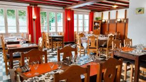 a restaurant with tables and chairs and red curtains at Hôtel Bellier in La Chapelle-en-Vercors