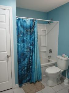 a bathroom with a blue shower curtain and a toilet at Dreamdoor Apartments in Moncton