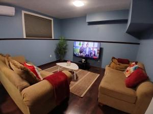 a living room with two couches and a flat screen tv at Dreamdoor Apartments in Moncton