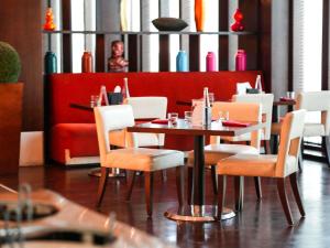a restaurant with a table and chairs and a red couch at Mövenpick Grand Al Bustan in Dubai