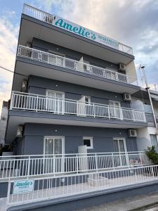 a tall building with white balconies and a sign on it at Amelies Apartments in Paralia Katerinis