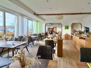 a restaurant with tables and chairs in a room with windows at Hotel zur Sonne in Bodelshausen