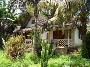 a house with palm trees in front of it at Hotel La Caravelle in Ambatoloaka