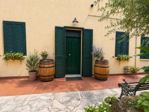 a building with green doors and two wooden barrels at B&B Il Fiocinino in Comacchio