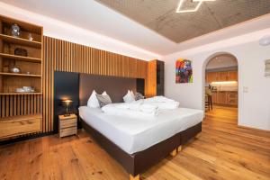a bedroom with a large bed with white sheets at Hotel Rupertihof in Ainring
