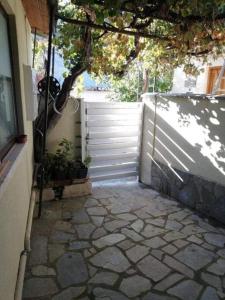 a stone walkway with a white fence and a tree at Aliki's Foini House in Phini