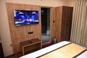 a bedroom with a television on a wooden wall at Florys Residency in Ooty