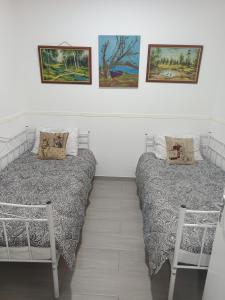 two beds in a room with paintings on the wall at Aliki's Foini House in Phini