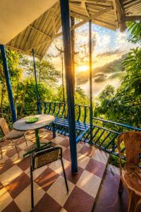 a room with a table and chairs on a balcony at munnar Green portico Cottages in Anachal