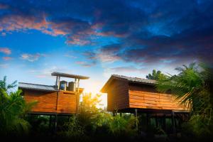 zwei Holzhäuser mit Sonnenuntergang im Hintergrund in der Unterkunft Sigiri Sarilco Rock View Treehouse in Sigiriya