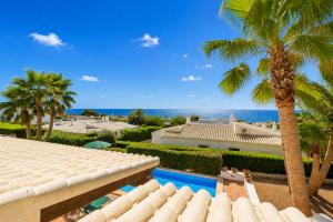 a view of a house with a swimming pool and palm trees at Villa Binipaco in Binibeca