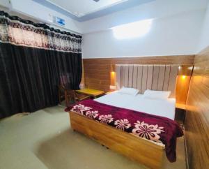 a bedroom with a large bed with a red blanket at Hotel Amrit in Bharwain