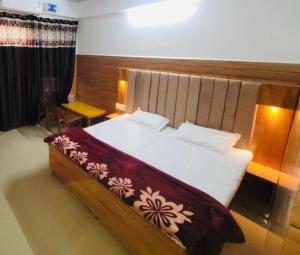 a bedroom with a large bed with a wooden headboard at Hotel Amrit in Bharwain