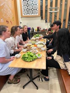 a group of people sitting around a table eating food at NinhBinh Central Homestay l Green Path in Xuân Sơn