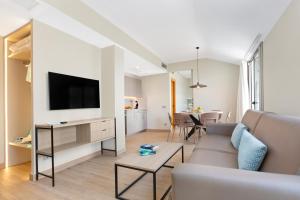 a living room with a couch and a tv at Aparthotel Odissea Park in Santa Susanna