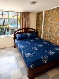 a bedroom with a bed with a blue comforter at Apartamento FullLife in Zipaquirá