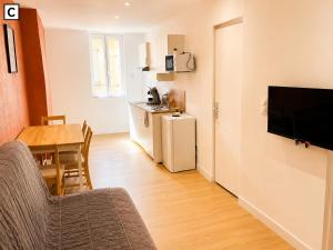 a living room with a table and a kitchen with a television at Notre Dame in Perpignan