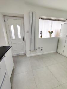a white kitchen with a door and a window at New Studio Near Science Park Cambridge in Cambridge