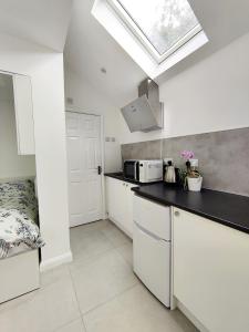a kitchen with white cabinets and a skylight at New Studio Near Science Park Cambridge in Cambridge