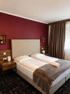 a bedroom with a large bed and a red wall at Zenith Hotel Frankfurt Airport in Kelsterbach