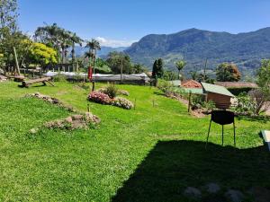 a green yard with a park with mountains in the background at Camping caminho das pedras in São Bento do Sapucaí