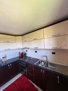 a kitchen with brown cabinets and a sink and a red rug at Hasan Nika's Tower in Karicë