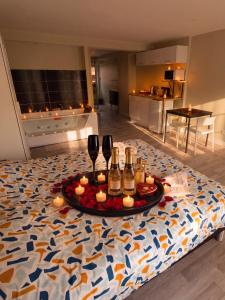 a table with wine glasses and candles on a bed at Loft Spa lumineux Jacuzzi privé écran cinéma in Roubaix