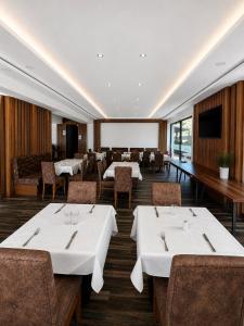 a restaurant with tables and chairs and a projection screen at Zenith Hotel Frankfurt Airport in Kelsterbach