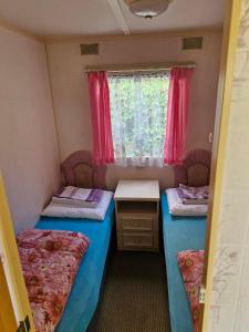 a small room with two beds and a window at Rodzinne Domki Łeba in Łeba