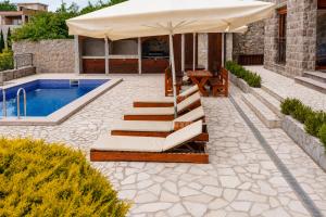 a patio with an umbrella and a swimming pool at Villa Vitanika in Kunjići