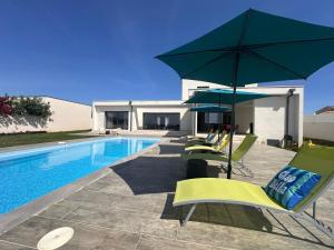 a pool with a group of chairs and an umbrella at Spacieuse villa standing de 220m2 à 5 minutes des plages in Aléria