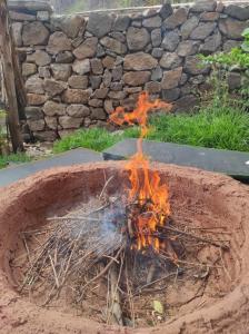 a fire in a pot in front of a stone wall at Casa Unupaccha in Calca