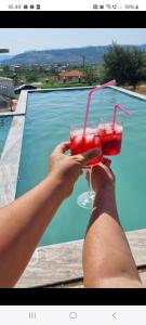 a person holding a drink in front of a pool at Kalanar villa in Elbasan