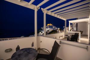 a balcony with a table and chairs at night at Galaxy studios in Astypalaia